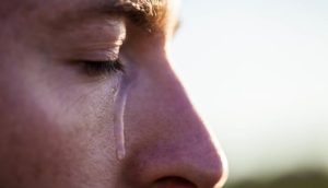 Man's face close up with a tear